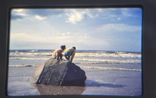 Twee kinderen op een rots in de zee, nieuwsgierig naar beneden kijkend